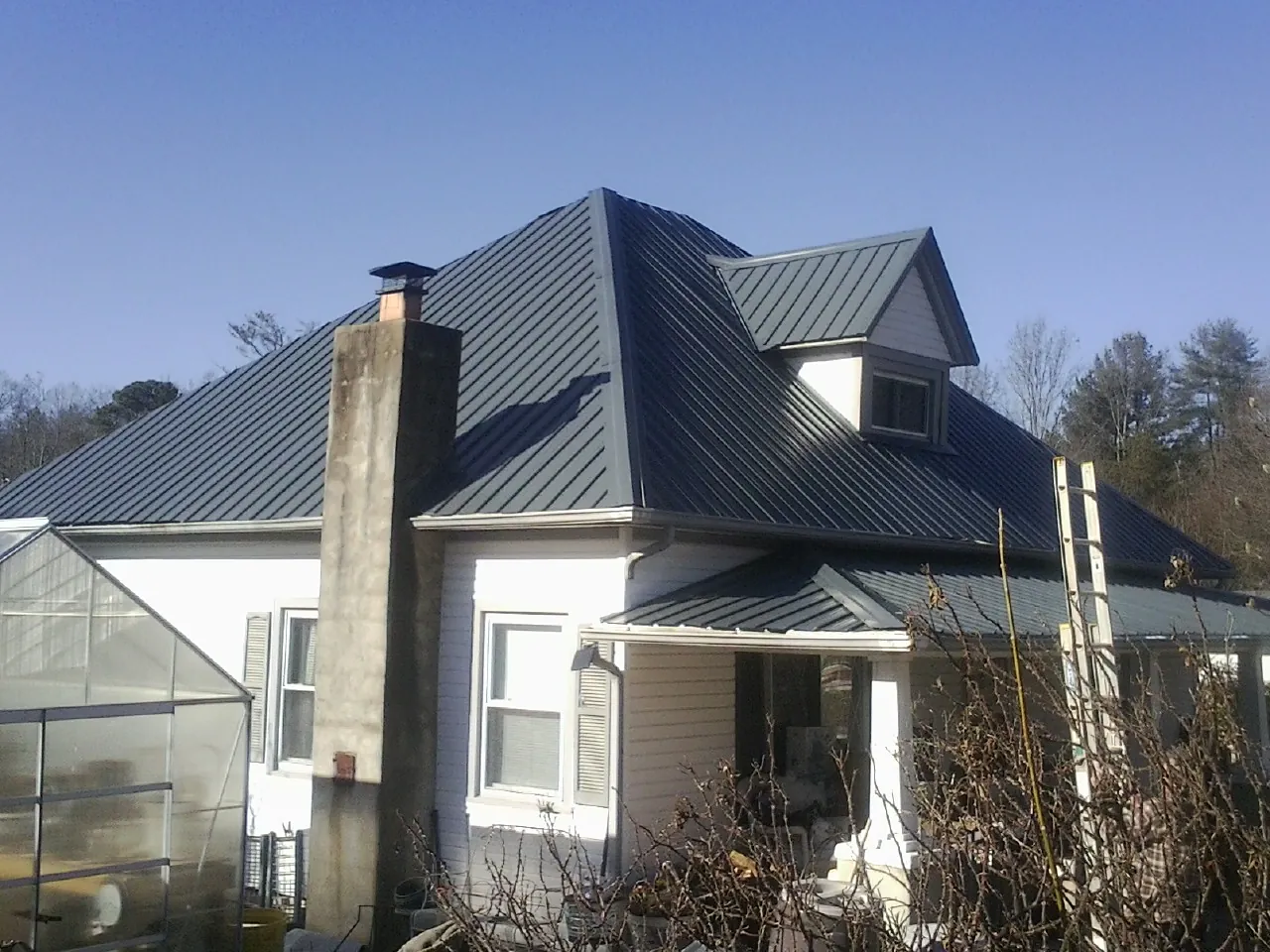Dark blue standing seam metal roof on a white farmhouse with dormer — Slate & Tile Roof Repair by Roofing Brothers in Sandersville
