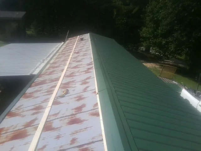 Old rusted panels beside newly installed green metal roofing — Wind Damage Roof Repair by Roofing Brothers in Sandersville