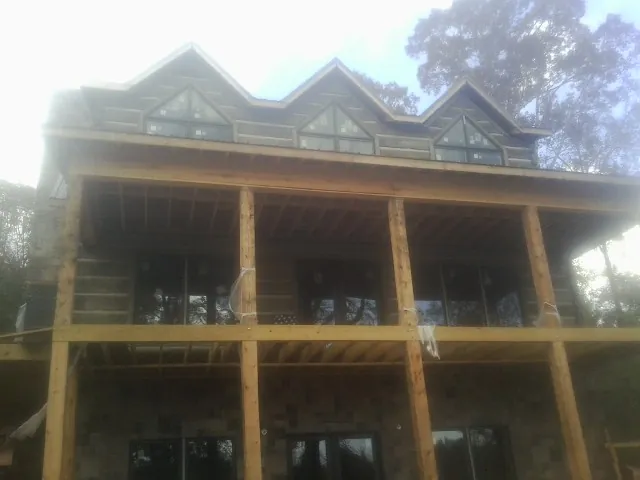 Dormers and porch framing on a large log home under construction — Roof Coating work by our crew in Sandersville