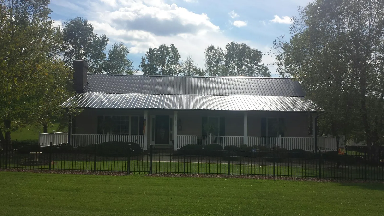 Gray metal roof on a brick ranch with a full width front porch — Gutter Guard Installation work by our crew in Sandersville