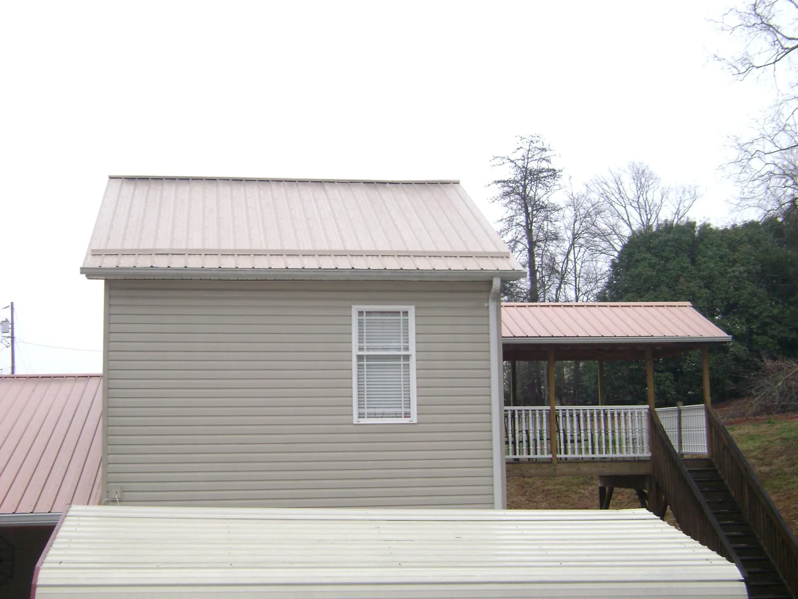 Tan metal roofs on a two story addition and attached porch, from a Roof Replacement job in Sandersville